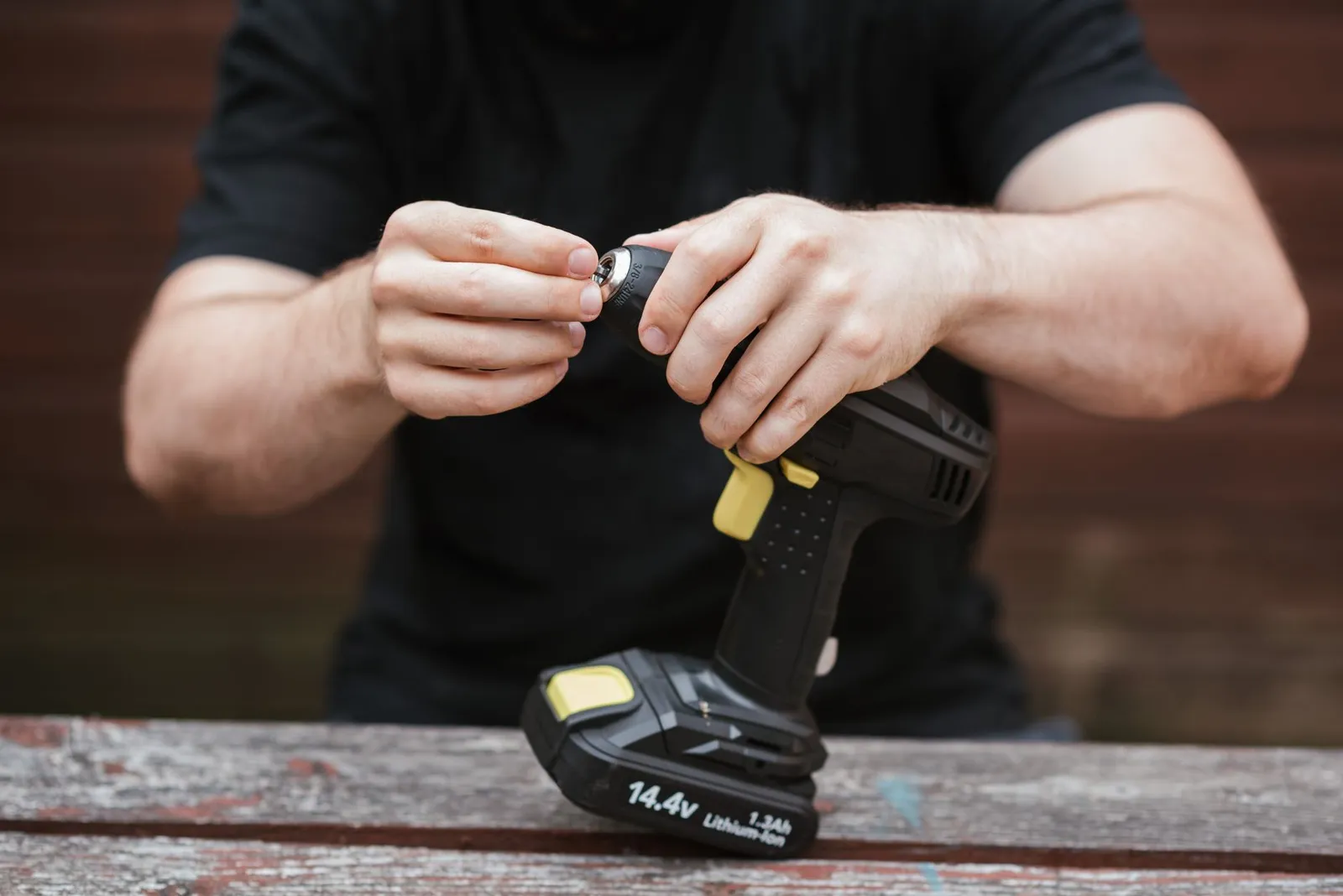 Perceuse sans fil au-dessus d'un établi, batterie lithium-ion marquée 14,4 V et 1,3 Ah bien visible