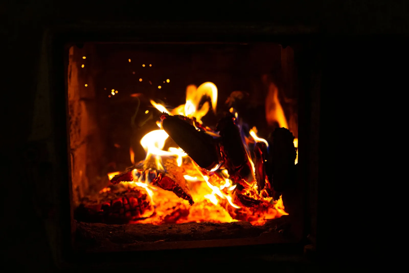 Flammes jaunes dansant dans le haut du foyer d'un poêle à bois vu à travers la vitre