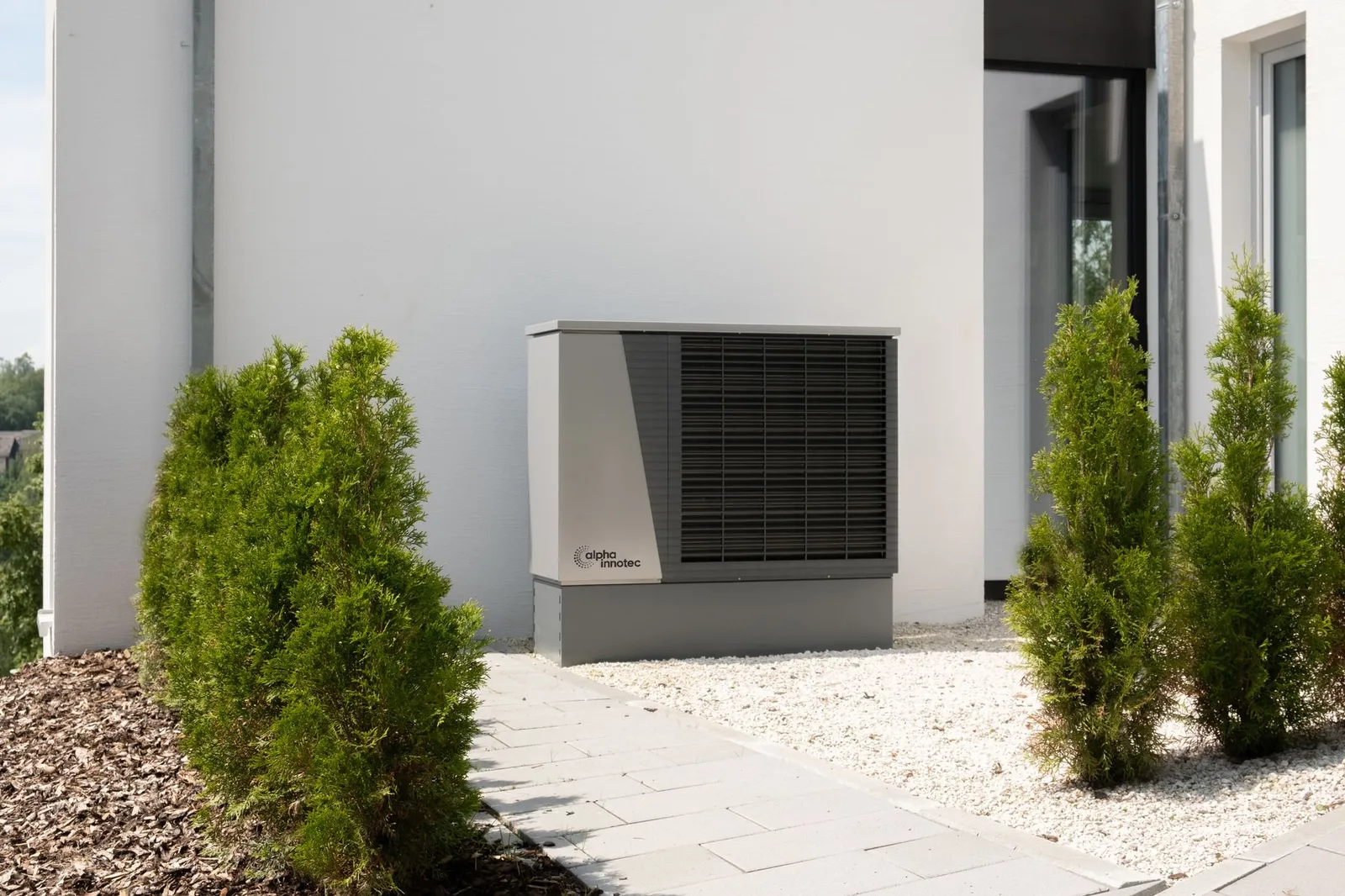 Unité extérieure de pompe à chaleur air-eau installée le long de la façade d'une maison
