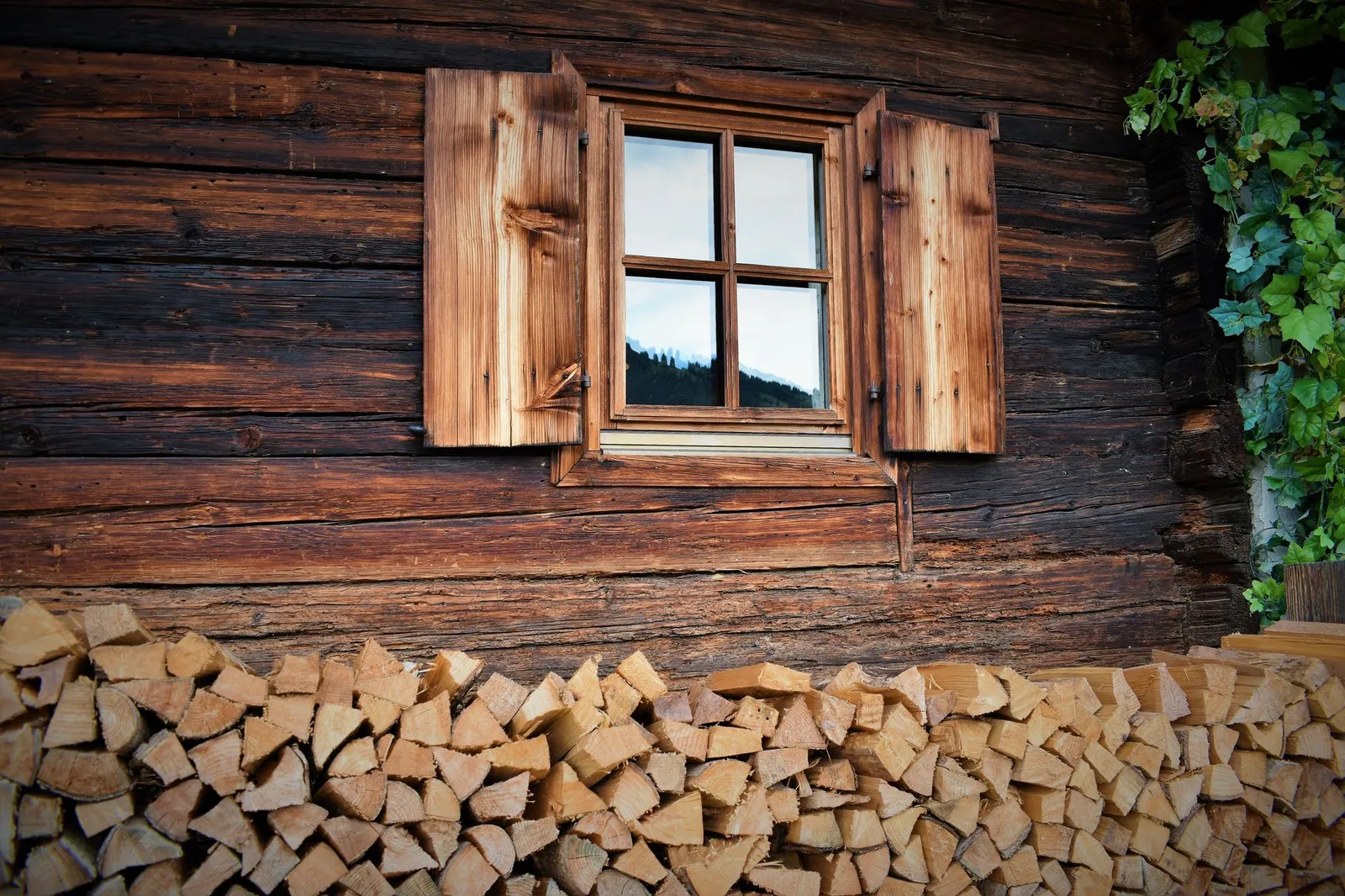 Grand tas de bûches empilées contre le mur d'une maison, prêt pour la saison de chauffe